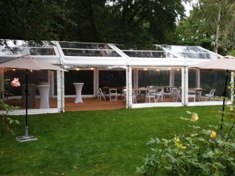 clear marquee in a garden for a summer party with coconut matting, tables and chairs